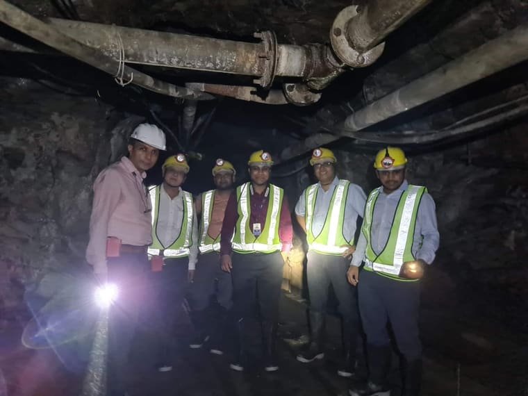 A team in helmets and high-visibility jackets in an underground working, lit by a hand torch