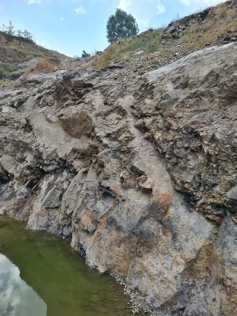 A cut rock face in the workings, with water standing at its foot